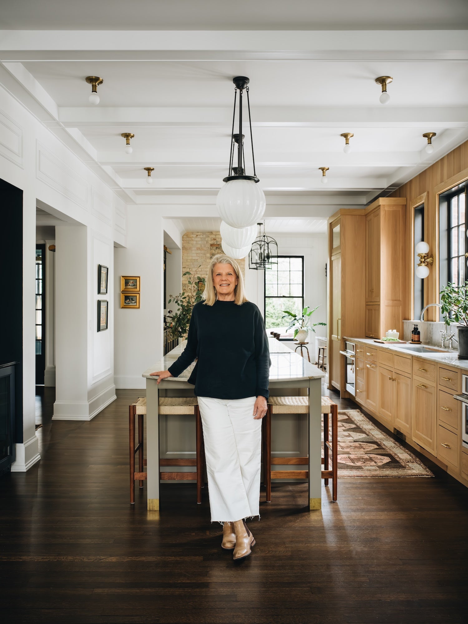 Woman standing in a modern kitchen with wooden cabinets and white walls.