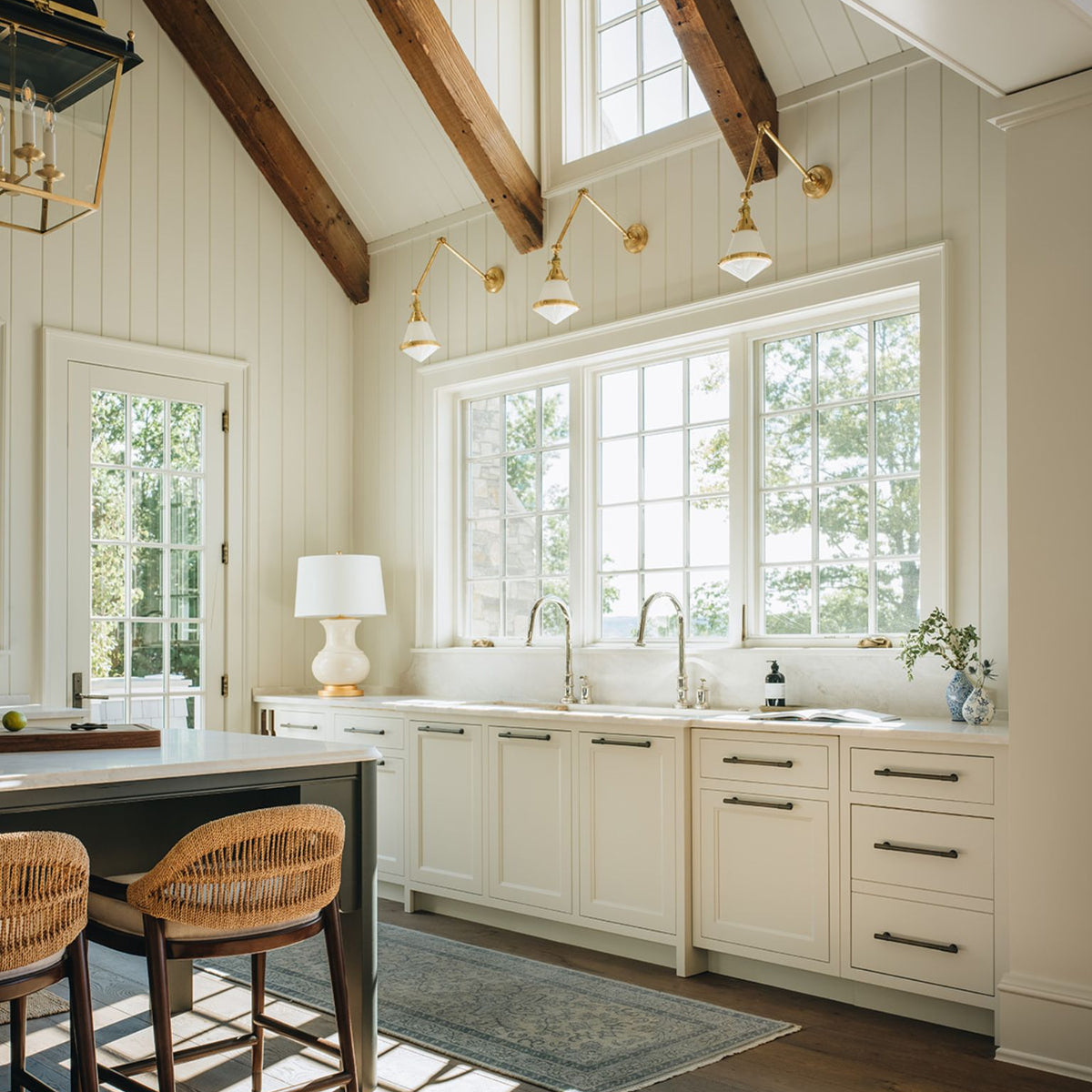 Modern kitchen with white cabinets, wooden beams, and natural light.
