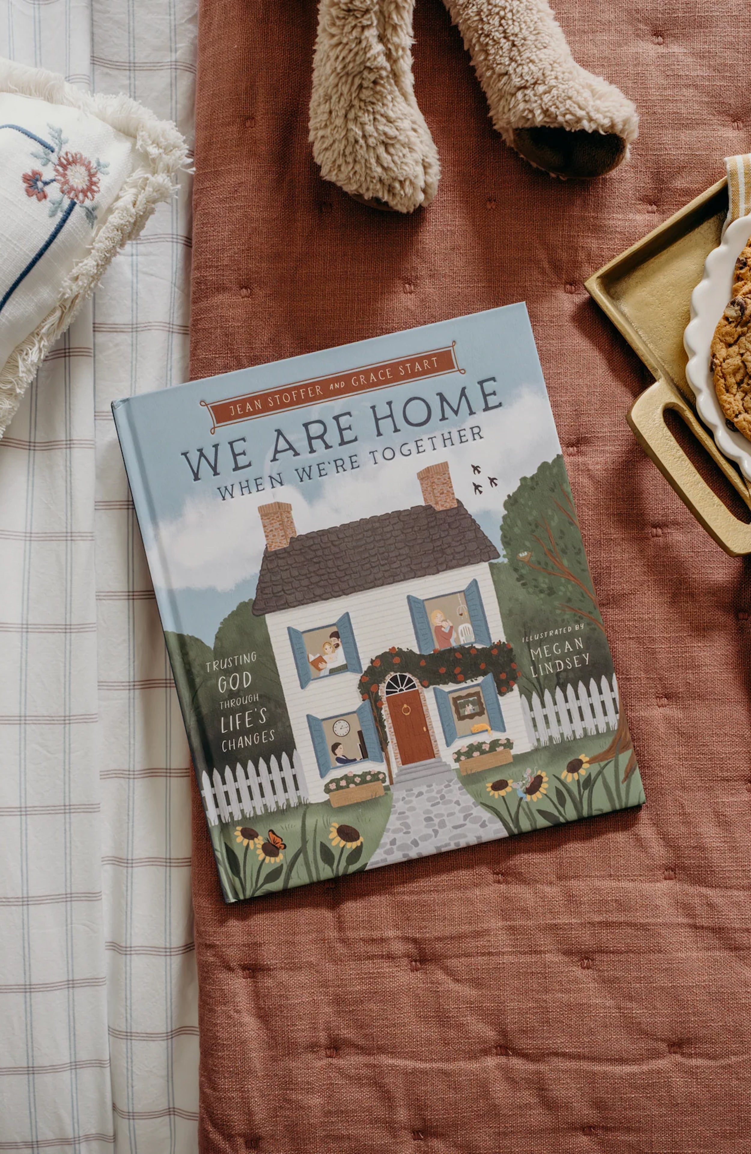 Book titled 'We Are Home When We're Together' on a wooden surface with decorative items.