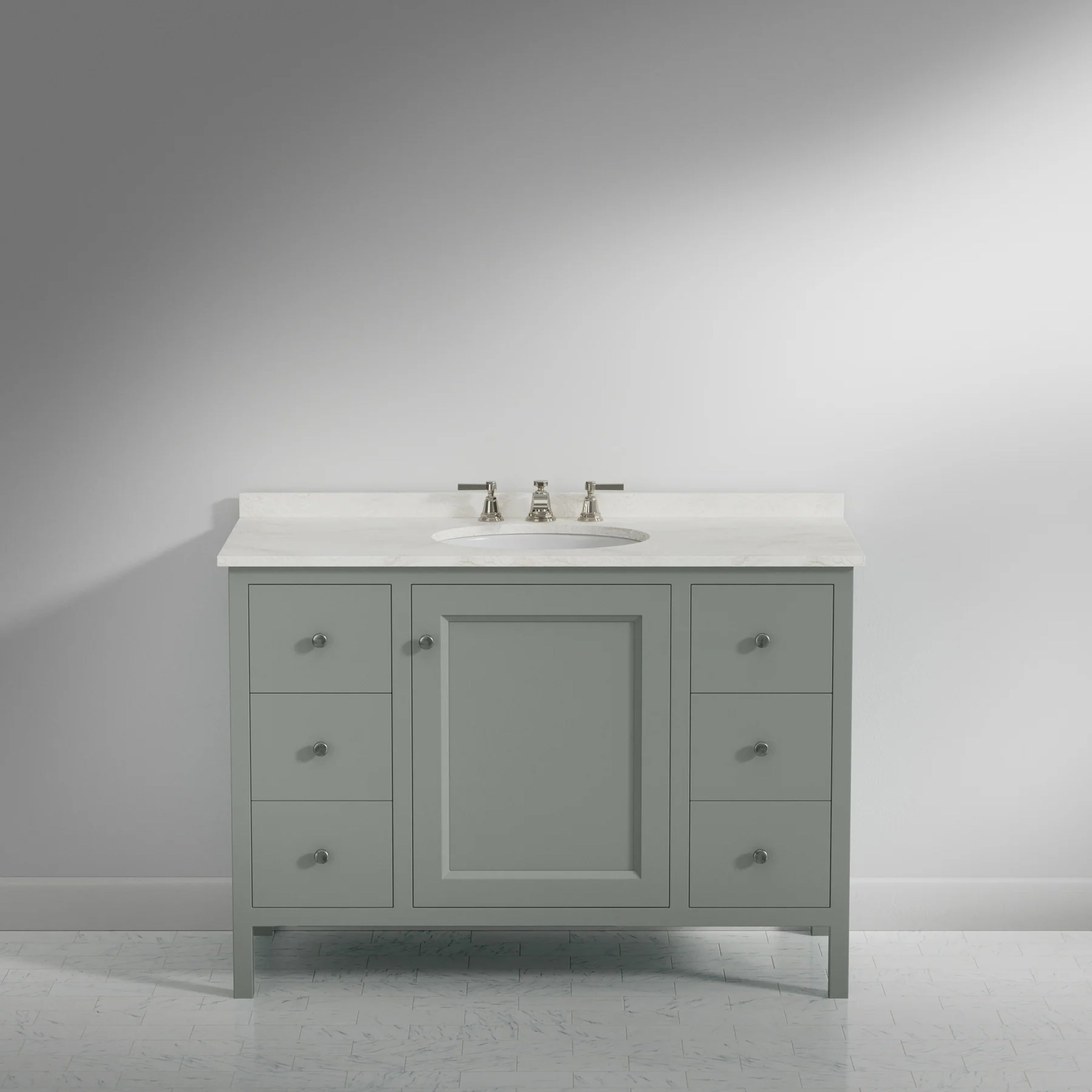 A single-sink bathroom vanity cabinet in a muted sage green finish with a white countertop and integrated sink, shown against a neutral gray studio background.